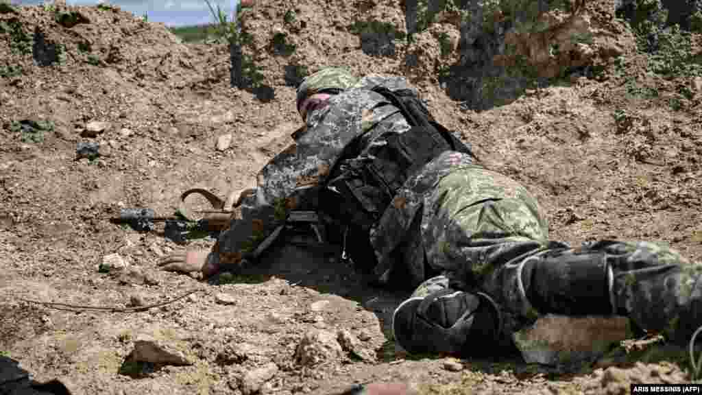 Український військовослужбовець ховається за земляним насипом під час обстрілу. Передмістя Лисичанська. Війна Росії проти України. 23 травня 2022 року