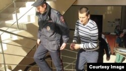 Павла Степанченко сопровождают в наручниках в здании Алуштинского городского суда, март 2017 года