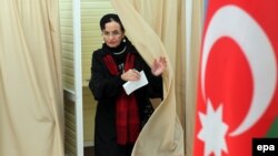 Azerbaijan -- A woman leaves a voting booth at a polling station in Baku, Azerbaijan, October 9, 2013