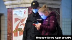 Москва, женщина показывает полицейскому QR-код для поездки в транспорте, 17 апреля 2020 года